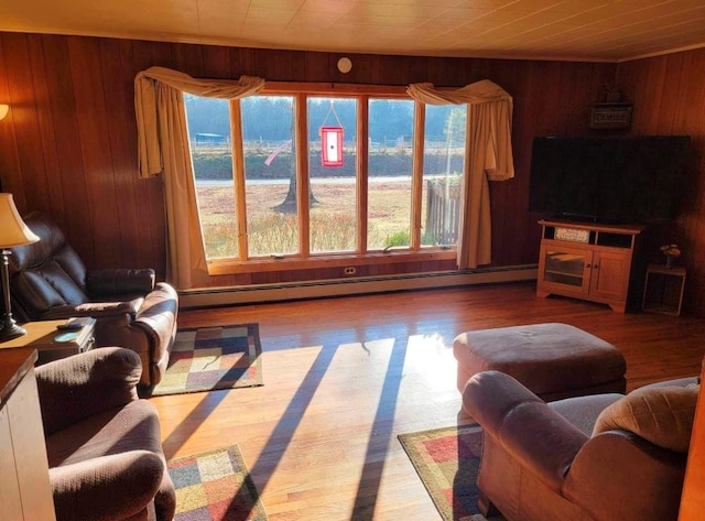 living room featuring baseboard heating, wood walls, and plenty of natural light