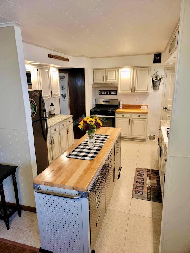 kitchen featuring wooden counters, black fridge, stainless steel gas stove, light tile patterned floors, and ornamental molding