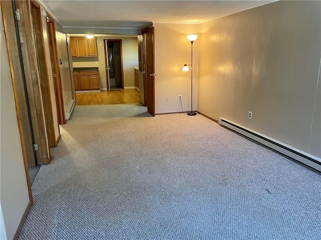 carpeted spare room featuring crown molding and a baseboard radiator