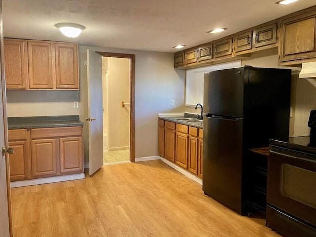 kitchen with black appliances, sink, and light hardwood / wood-style flooring