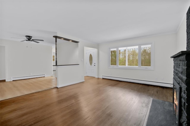 unfurnished living room with baseboard heating, a stone fireplace, ceiling fan, and hardwood / wood-style flooring