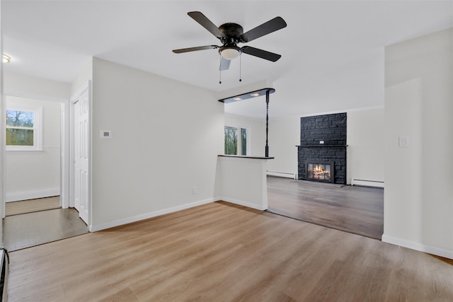 unfurnished living room with light hardwood / wood-style floors, a stone fireplace, and plenty of natural light