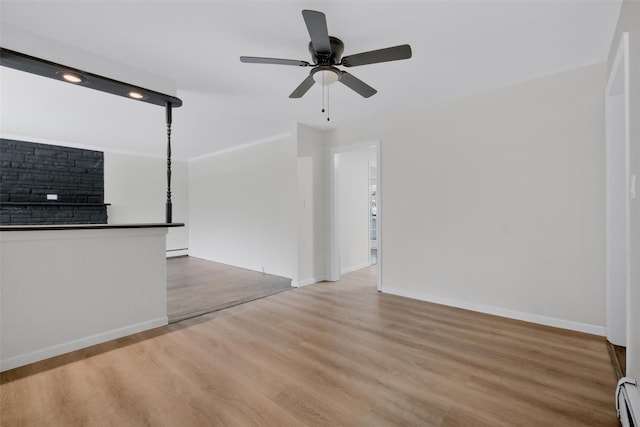 unfurnished living room with light wood-type flooring, ceiling fan, and a baseboard heating unit