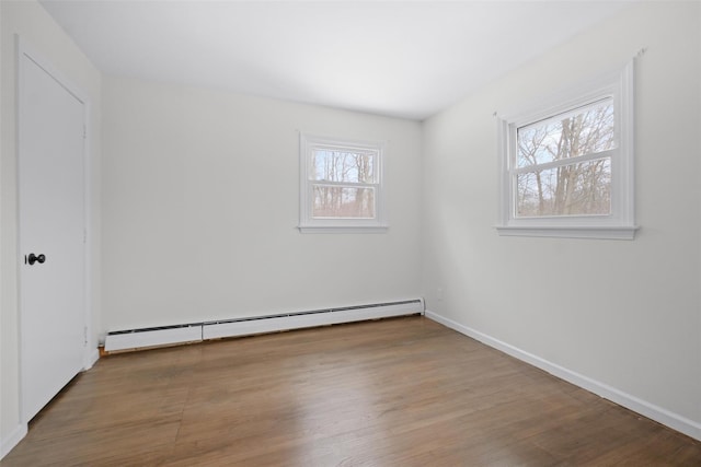 unfurnished room featuring hardwood / wood-style flooring and baseboard heating