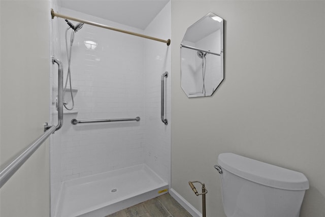 bathroom with hardwood / wood-style flooring, toilet, and tiled shower