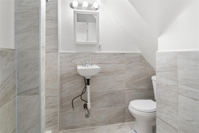 bathroom featuring toilet and tile walls