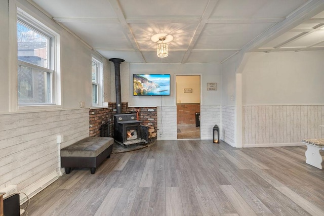 living room featuring a wood stove, hardwood / wood-style floors, and coffered ceiling