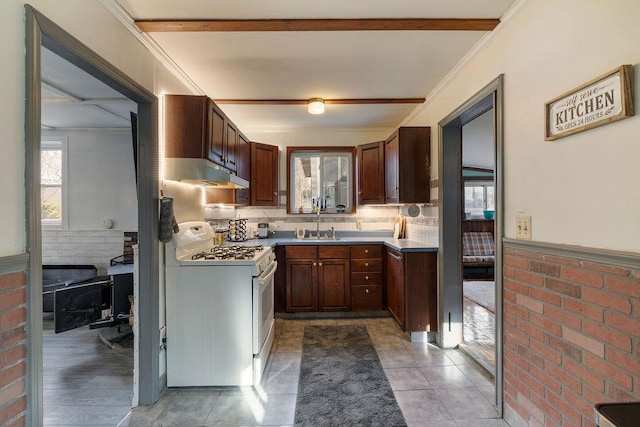 kitchen featuring backsplash, crown molding, sink, white gas range, and beam ceiling