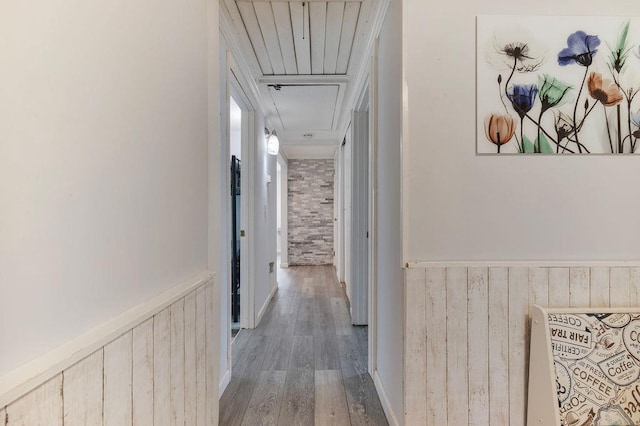 hallway with hardwood / wood-style floors, wooden walls, and brick wall