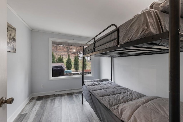 bedroom with baseboard heating, crown molding, and hardwood / wood-style floors