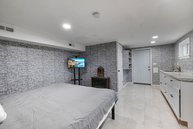 bedroom with light tile patterned floors, sink, and brick wall