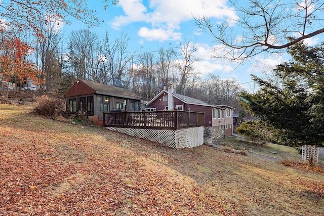 rear view of property with a sunroom, a deck, and a lawn