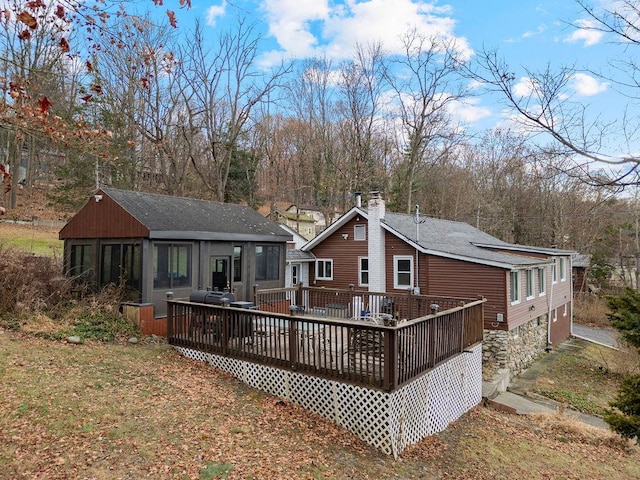 rear view of property featuring a sunroom and a deck