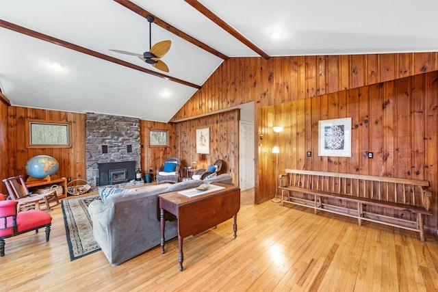 living room with wood walls, high vaulted ceiling, light hardwood / wood-style flooring, ceiling fan, and beam ceiling