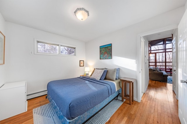 bedroom featuring light hardwood / wood-style flooring, baseboard heating, and multiple windows