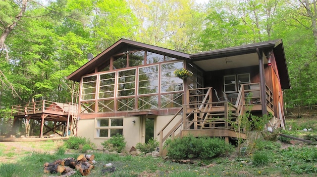 rear view of property featuring a sunroom and a wooden deck