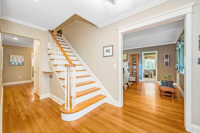 stairway with ornamental molding, baseboards, and wood finished floors