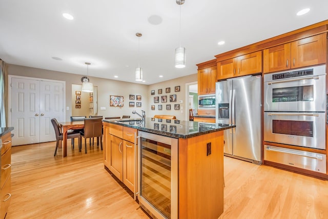 kitchen featuring a warming drawer, light wood-type flooring, stainless steel appliances, wine cooler, and brown cabinets