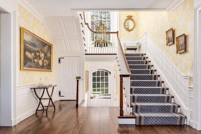 stairway with a wainscoted wall, crown molding, wood finished floors, and wallpapered walls