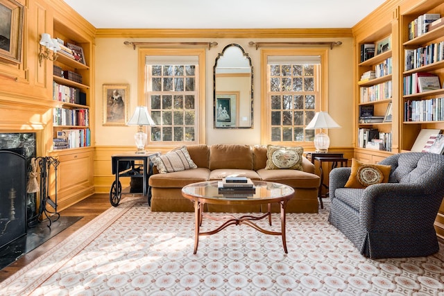 living area with crown molding, light hardwood / wood-style floors, a fireplace, and built in shelves