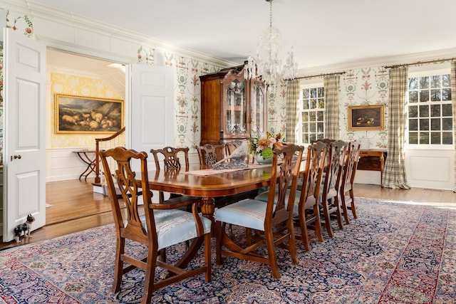 dining room with wallpapered walls, wood finished floors, crown molding, and a wainscoted wall