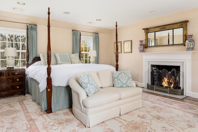 bedroom with a warm lit fireplace and visible vents