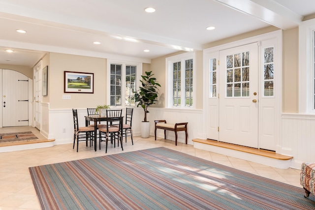 interior space with recessed lighting, beam ceiling, a wainscoted wall, and light tile patterned floors