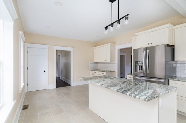 kitchen featuring stainless steel fridge, backsplash, pendant lighting, white cabinets, and a kitchen island