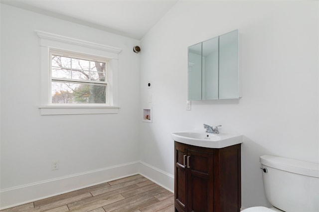 bathroom featuring hardwood / wood-style floors, vanity, toilet, and vaulted ceiling