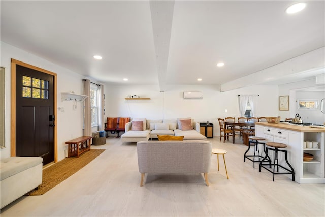 living room featuring beamed ceiling, light wood-type flooring, and a wall unit AC