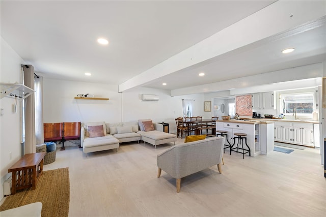 living room with beam ceiling, light hardwood / wood-style floors, a wall mounted AC, and sink