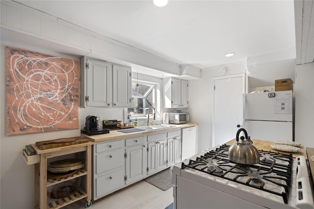 kitchen with white appliances, light hardwood / wood-style flooring, and sink