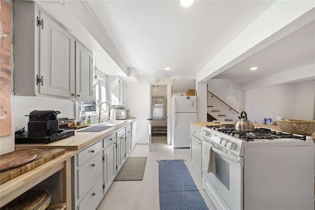 kitchen with sink, wooden counters, white appliances, and light wood-type flooring