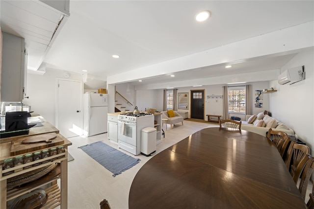 kitchen featuring a wall mounted air conditioner, white appliances, light wood-type flooring, beamed ceiling, and white cabinetry