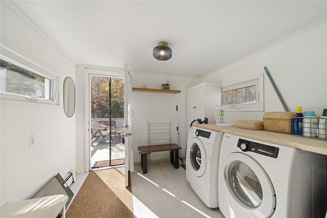 clothes washing area featuring cabinets, washing machine and dryer, and crown molding