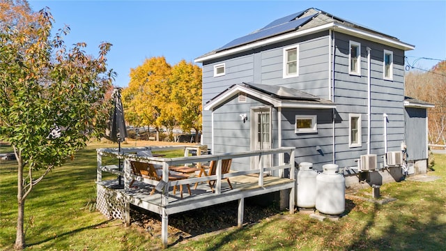 back of property featuring solar panels, a lawn, and a wooden deck