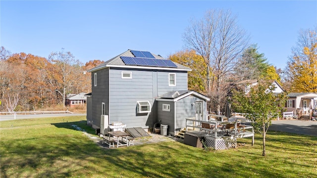 back of house with a lawn, solar panels, and a wooden deck