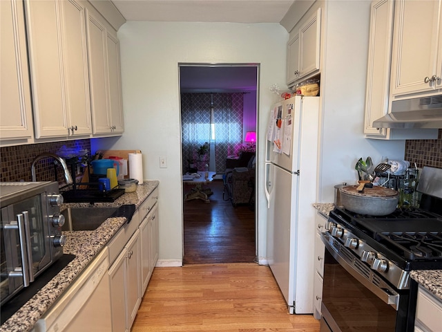 kitchen with white cabinets, white appliances, light hardwood / wood-style floors, and tasteful backsplash