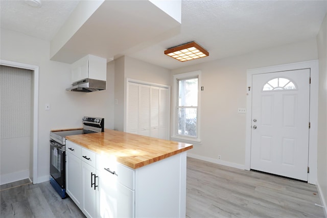 kitchen featuring light wood finished floors, stainless steel electric range, under cabinet range hood, wood counters, and white cabinetry