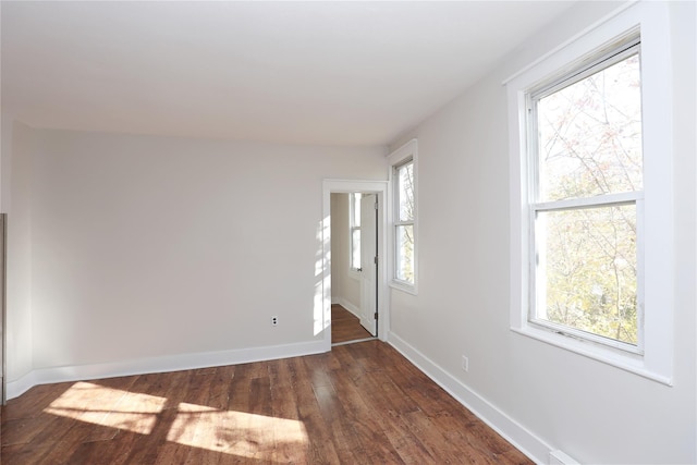 spare room featuring baseboards and dark wood-style flooring