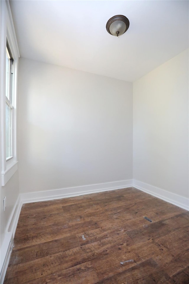 spare room featuring dark wood-style floors and baseboards