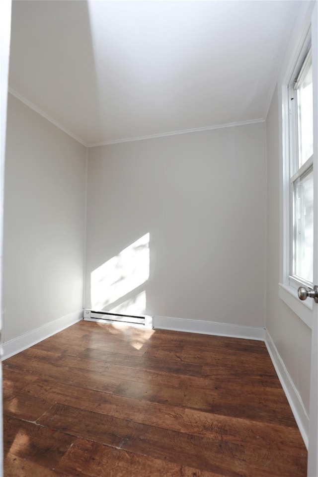 spare room featuring baseboards, baseboard heating, wood finished floors, and ornamental molding