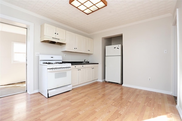 kitchen with dark countertops, under cabinet range hood, light wood-type flooring, ornamental molding, and white appliances