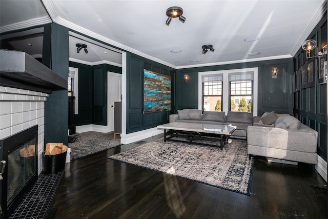 living room featuring dark hardwood / wood-style flooring, ornamental molding, and a tiled fireplace