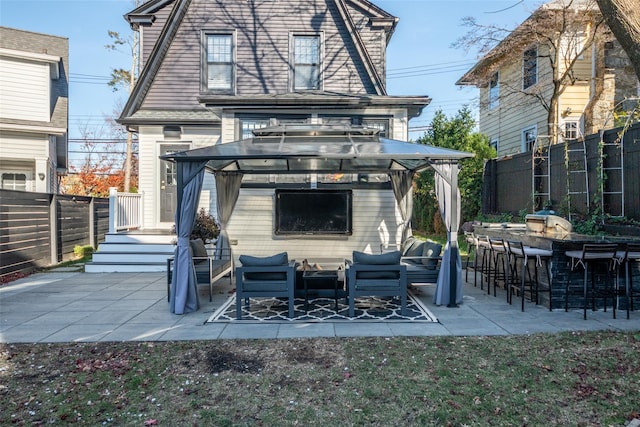 back of house with a gazebo, a bar, and a patio area