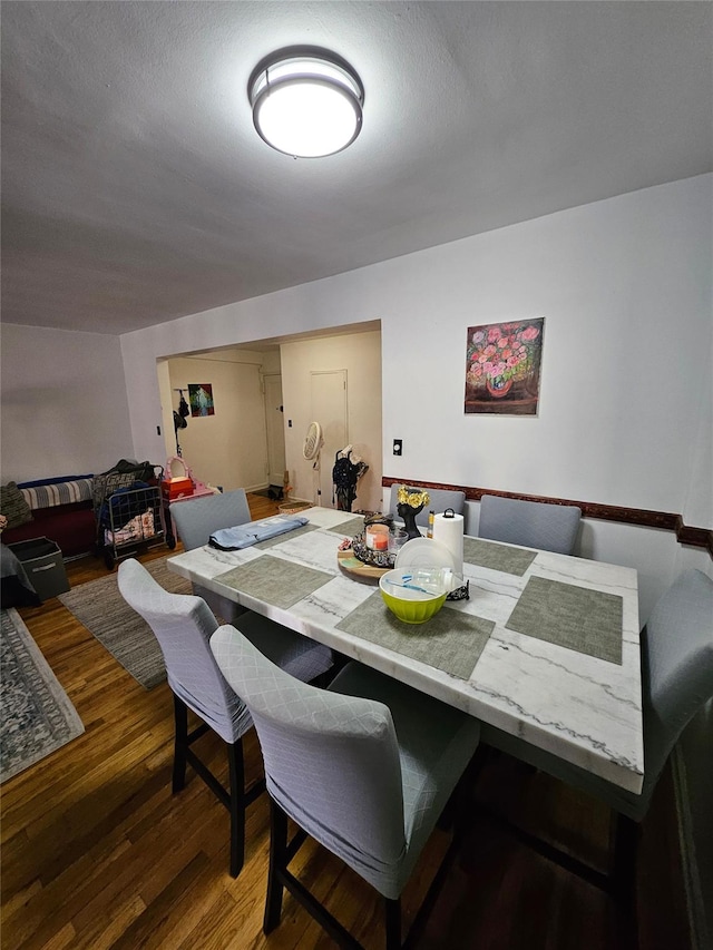 dining area with a textured ceiling and dark wood-type flooring