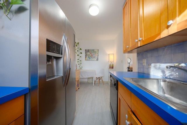 kitchen with backsplash, light wood-type flooring, sink, and appliances with stainless steel finishes