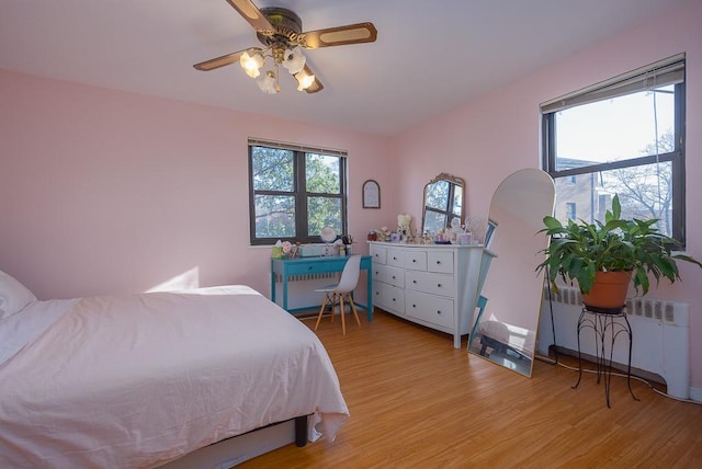 bedroom with radiator, ceiling fan, and light wood-type flooring