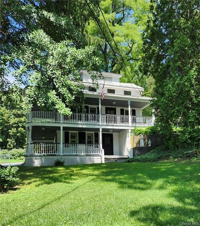 rear view of house featuring a yard and a balcony