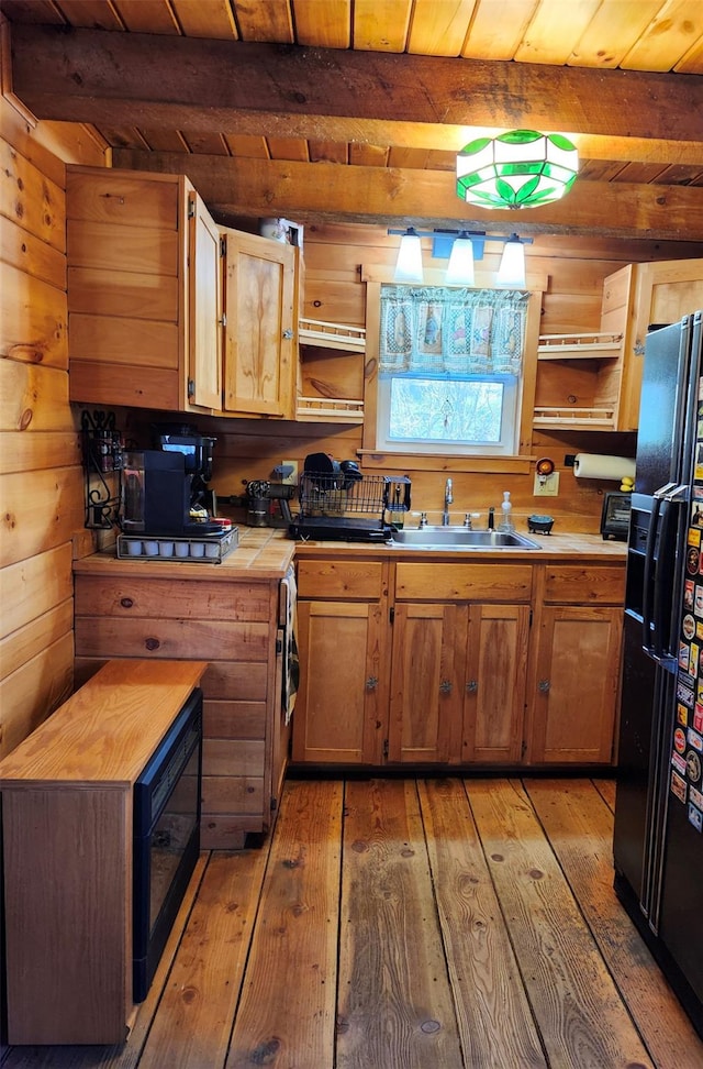 kitchen featuring wooden ceiling, black fridge, sink, beamed ceiling, and light hardwood / wood-style floors